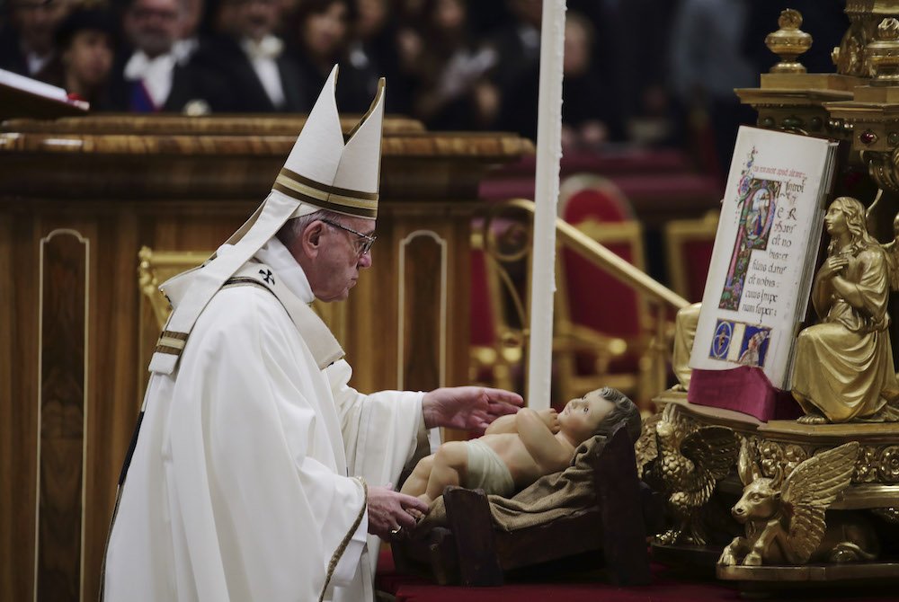 Pope Francis venerates a figurine of the baby Jesus at the conclusion of Christmas Eve Mass in St. Peter's Basilica at the Vatican Dec. 24. (CNS photo/Evandro Inetti