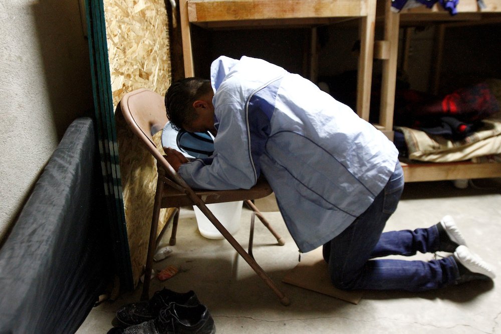 A Honduran migrant prays at a shelter in Tijuana