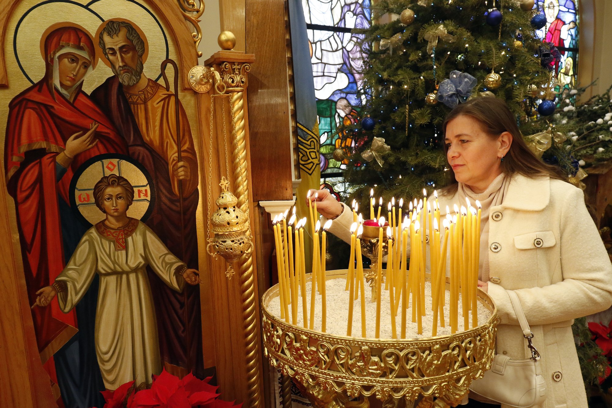 A woman lights a candle prior to a Divine Liturgy marking the feast of the Nativity Jan. 7