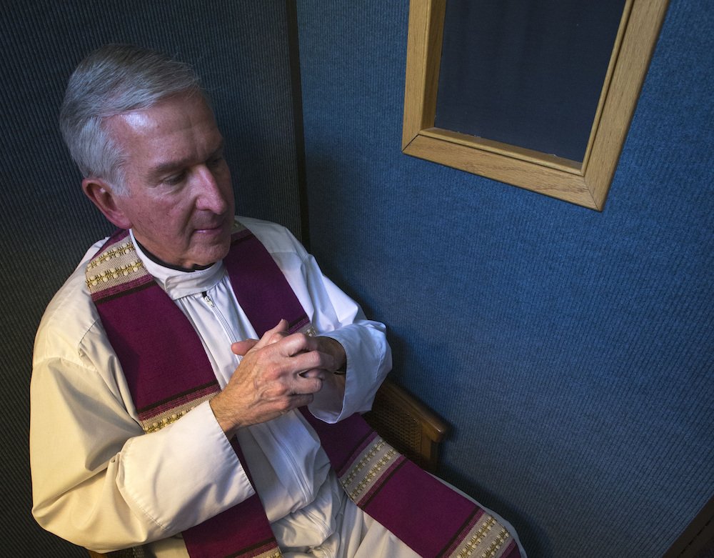 Father Timothy J. Mockaitis demonstrates how he hears confession. (CNS photo/Chaz Muth)