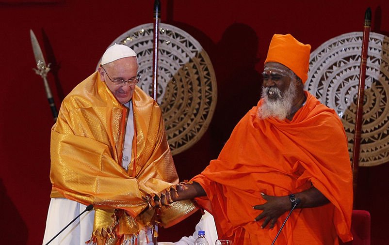 Pope Francis shakes hands with Hindu Kurukkal SivaSri T. Mahadeva after receiving a robe from him during a meeting with religious leaders at the Bandaranaike Memorial International Conference Hall in Colombo