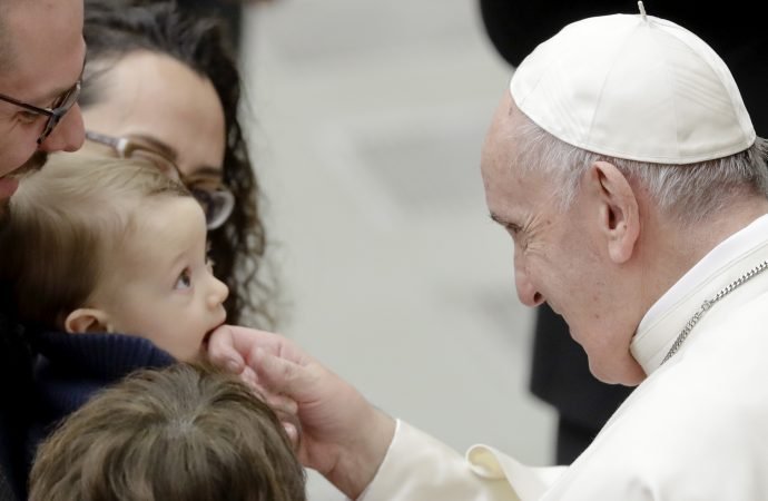 Pope Francis caresses a baby during an audience with Vatican employees in the Pope Paul VI hall
