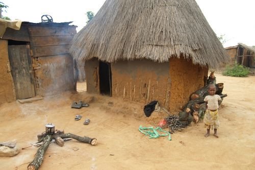 A young boy stands in front of a simple mud hut in a village in the Diocese of Chinhoyi