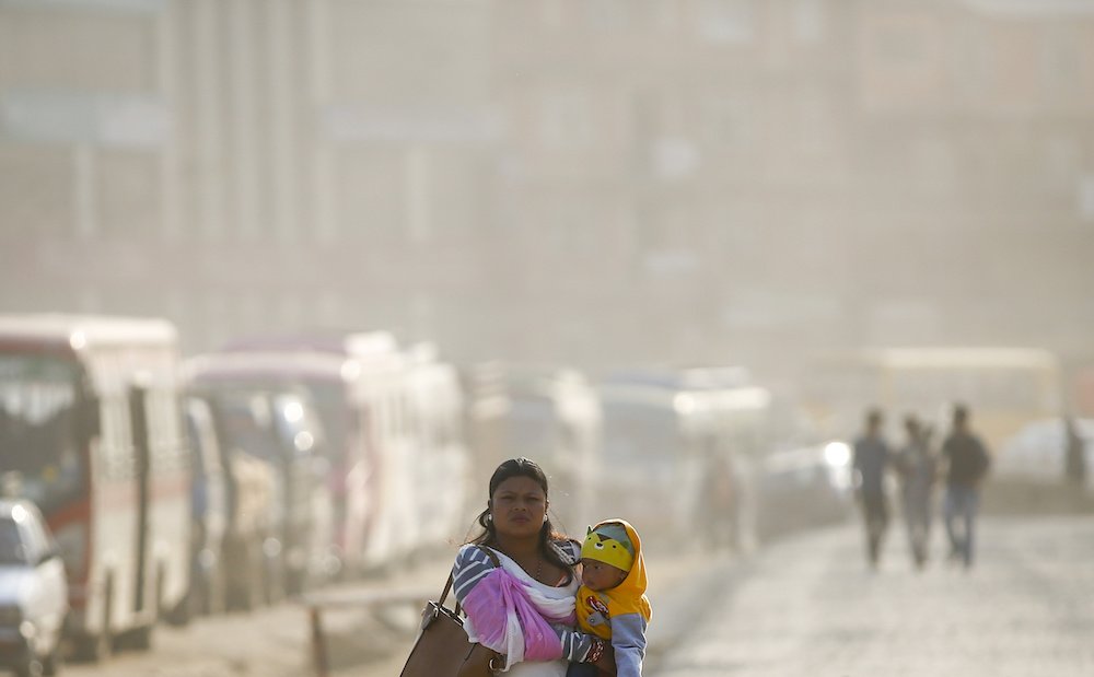 A woman carries a child through air pollution in Kathmandu