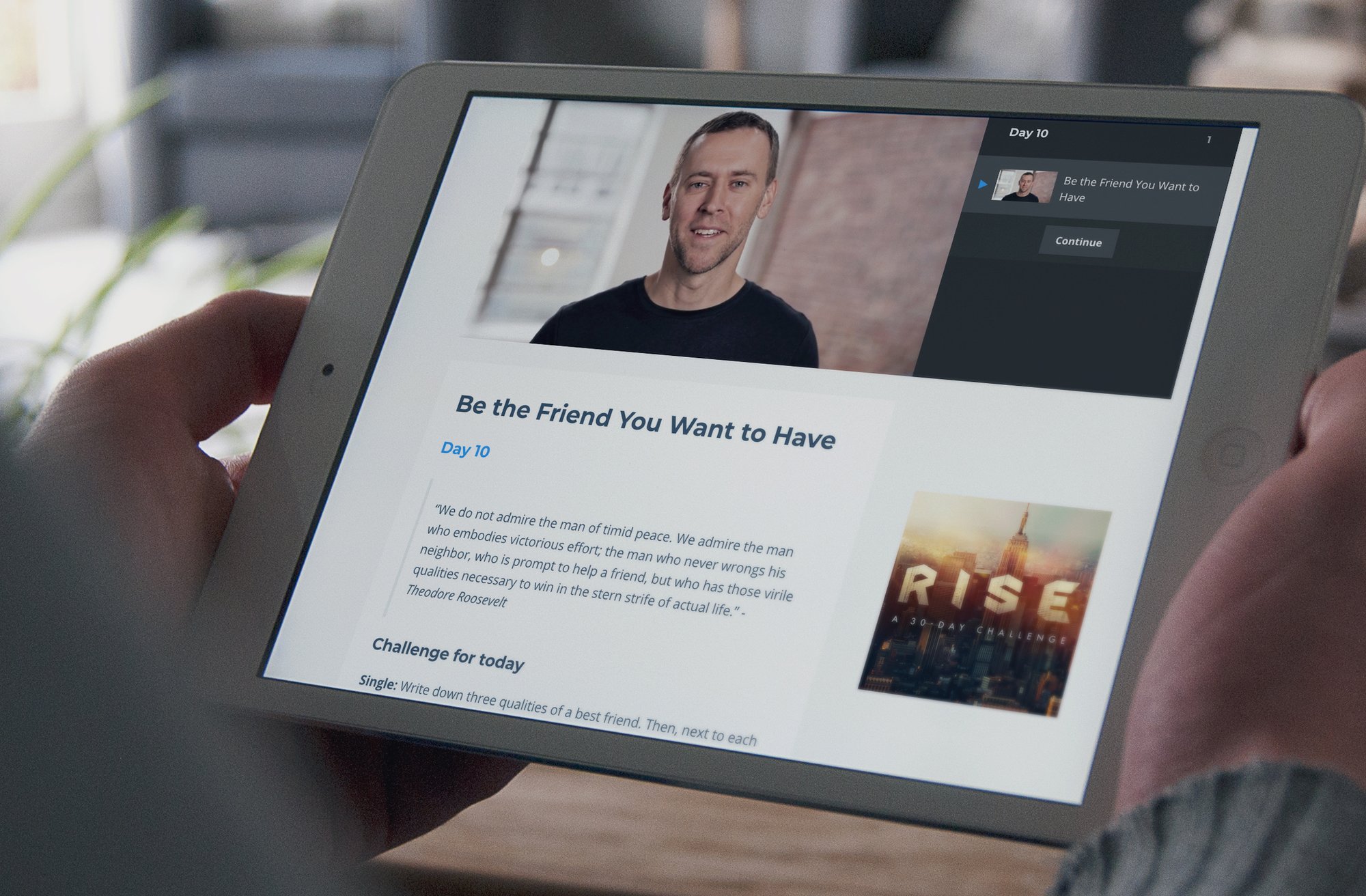 A man holds a tablet that is displaying a website for RISE