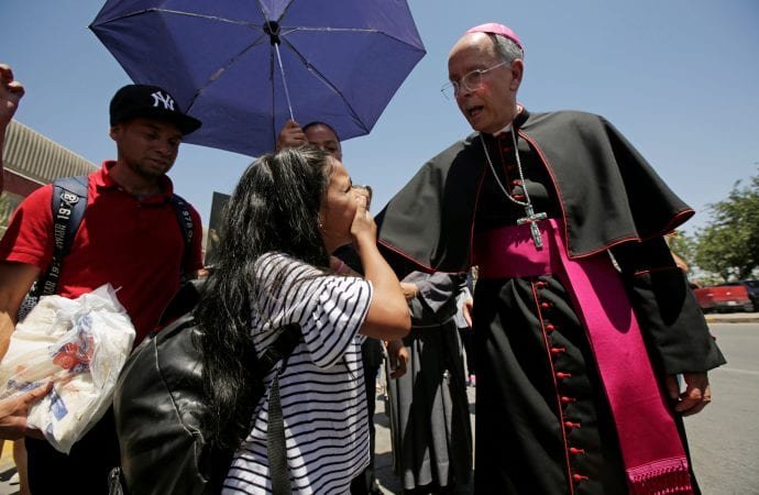 Bishop Mark J. Seitz of El Paso, Texas, talks with a Honduran girl, Cesia, while walking and praying with a group of migrants at the Lerdo International Bridge in El Paso June 27, 2019. The migrants were seeking asylum in the U.S. (CNS via Crux)