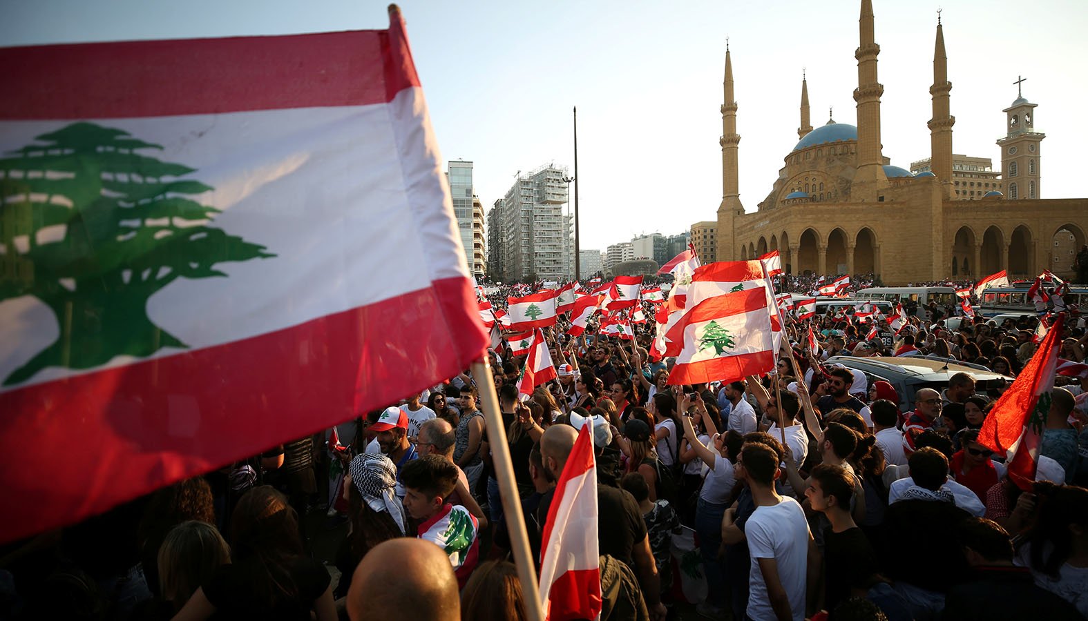 Demonstrators near Al-Amin mosque in Beirut carry national flags during an anti-government protest Oct. 20, 2019. Fueled by economic insecurity and deteriorating living conditions, protests were sparked by government plans to impose new taxes. (CNS photo/Ali Hashisho, Reuters)
