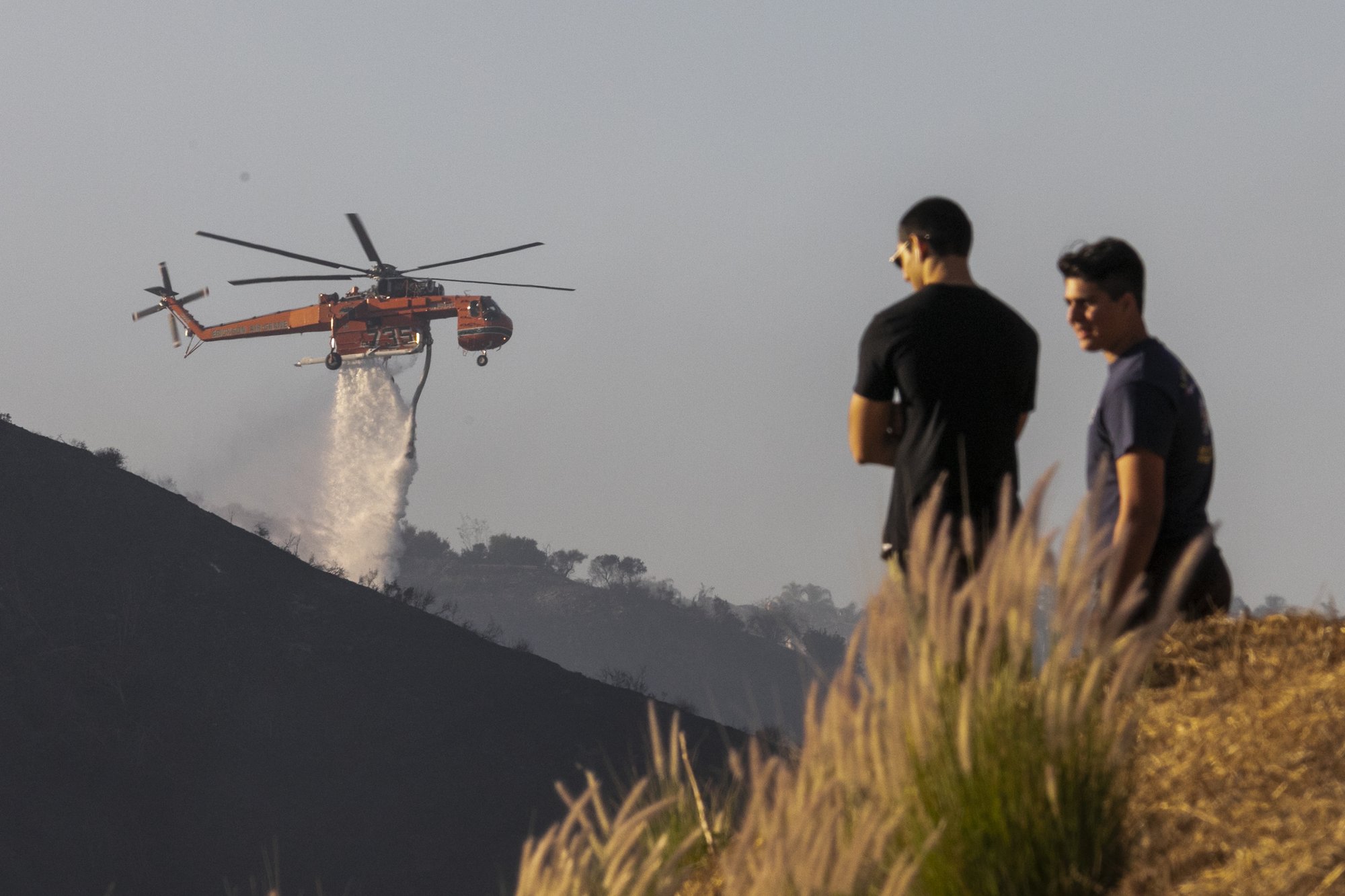 People watch helicopters make water drops on the Getty Fire on October 28, 2019 in Los Angeles. (Photo by David McNew/Getty Images)