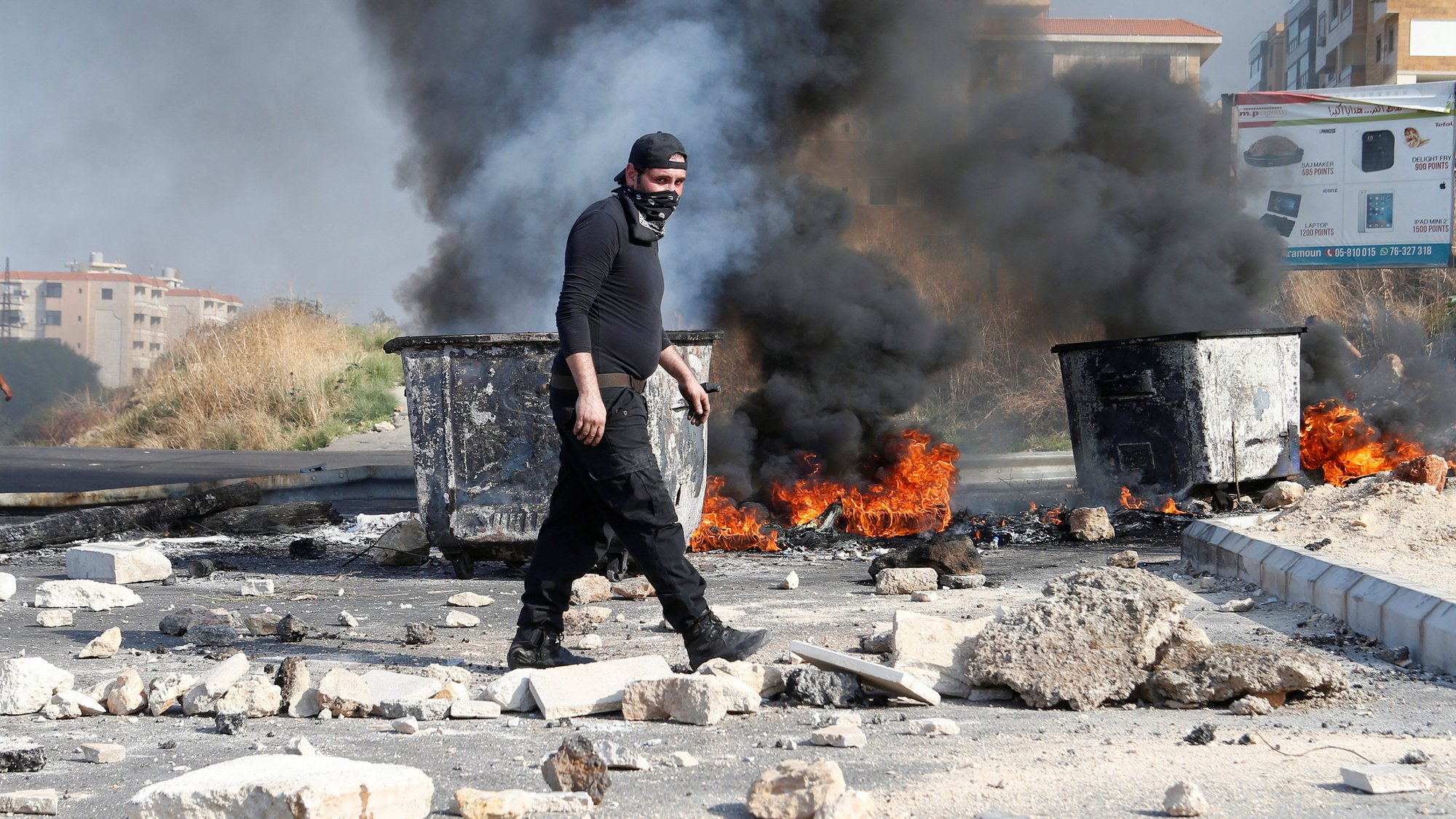 A demonstrator walks near burning tires barricading a road during ongoing anti-government protests in Khaldeh, Lebanon, Nov. 13, 2019. (CNS photo/Mohamed Azakir, Reuters)