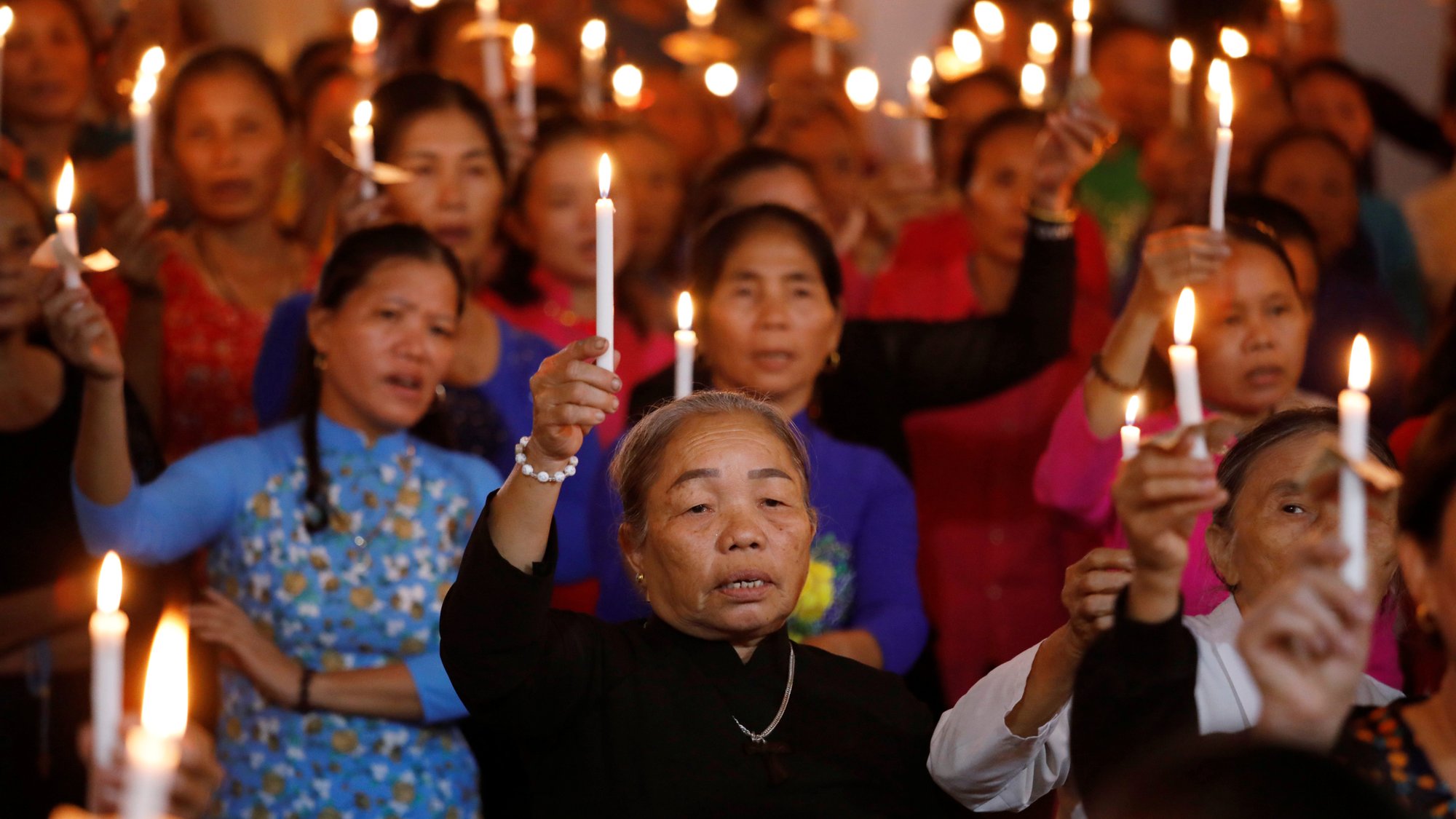Women hold candles during a service at a church in My Khanh, Vietnam, Oct. 26, 2019, for 39 Vietnamese migrants found dead in the back of a truck at the Port of Tilbury in Essex, England. In a message to young Catholics in Vietnam, Pope Francis offered prayers for the migrants, who died while being smuggled into Great Britain in late October. (CNS photo/Kham, Reuters)