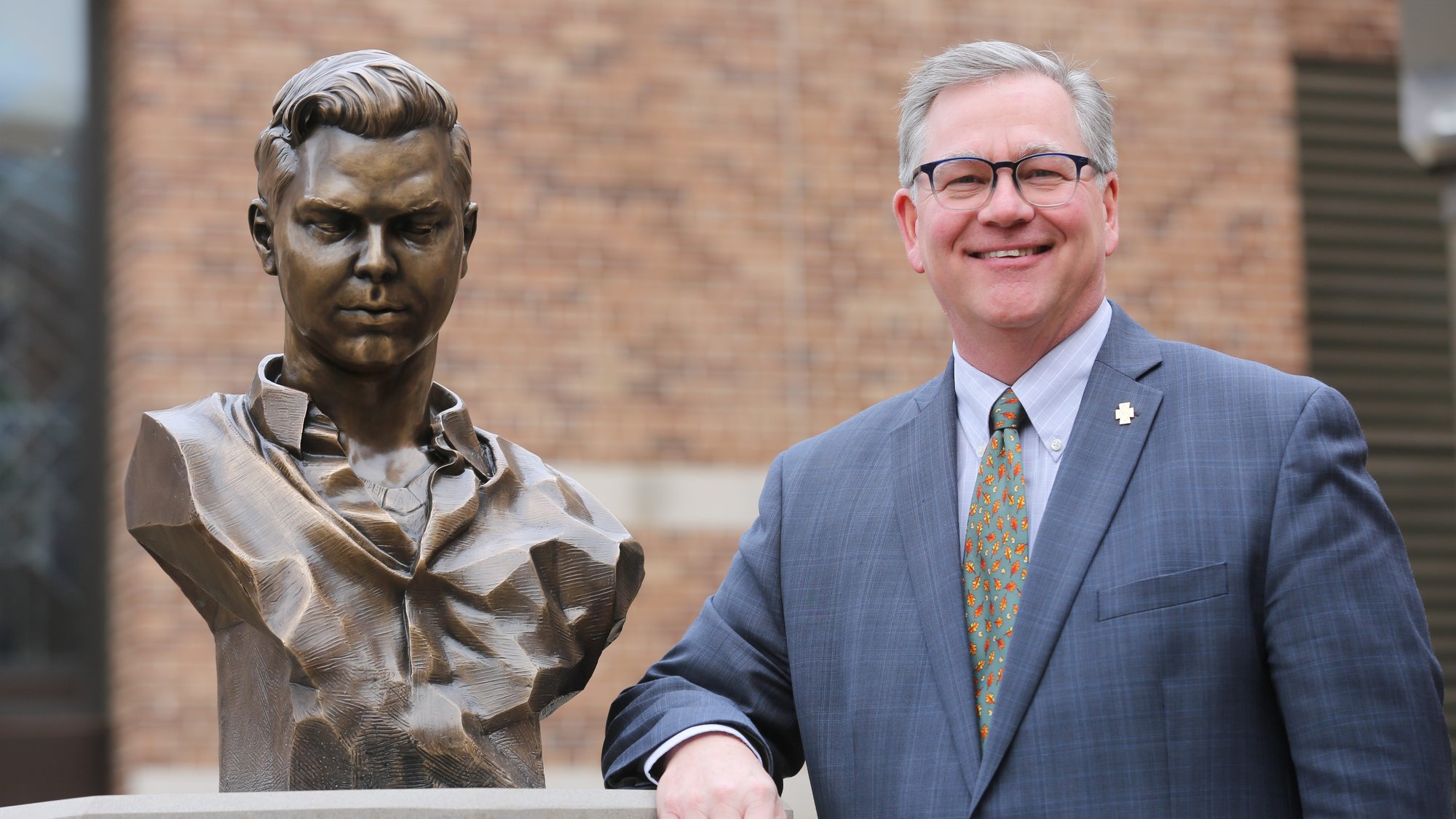 Frank Miley, president of Cretin-Derham Hall High School in St. Paul, Minn., stands next to a bronze bust of Brother James Miller that sits in the courtyard of the school. Brother Miller, who taught at the school from 1966-1971 and again from 1979-1980, was officially recognized by Pope Francis as a martyr last year, clearing the way for beatification. He will be beatified Dec. 7 in Guatemala. (CNS photo/Dave Hrbacek, Catholic Spirt)