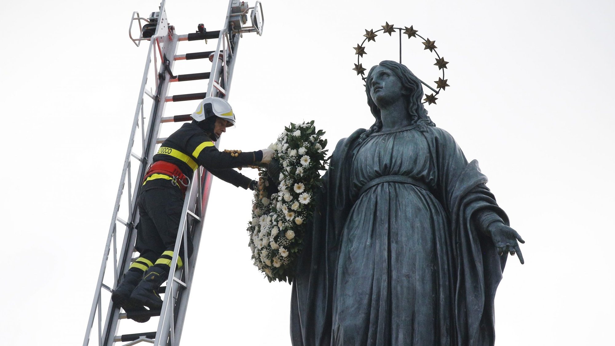 A firefighter places a wreath on a Marian statue overlooking the Spanish Steps in Rome Dec. 8, 2019, the feast of the Immaculate Conception. (CNS photo/Paul Haring)