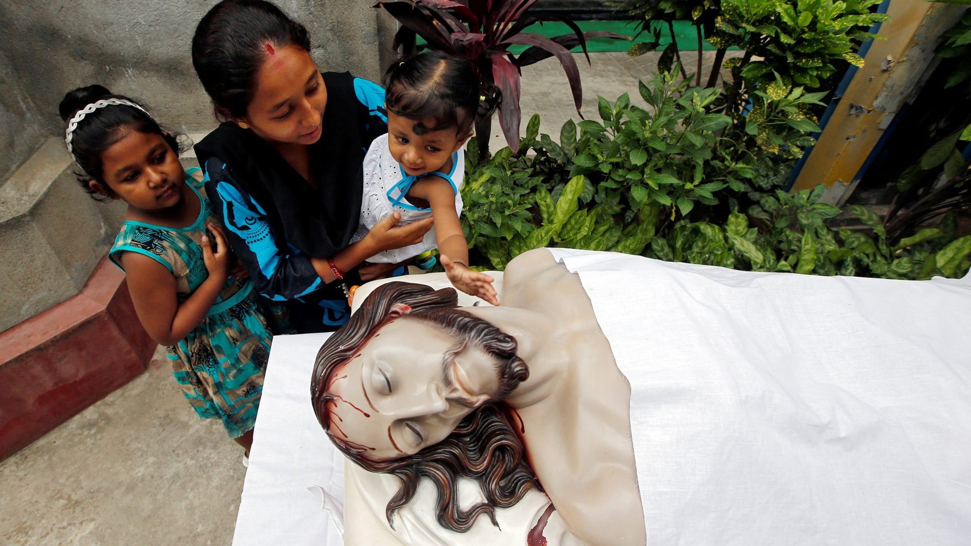 A woman in Kolkata, India, helps her daughter touch a statue of Jesus after attending a Good Friday service April 19, 2019. (CNS photo/Rupak De Chowdhuri, Reuters)