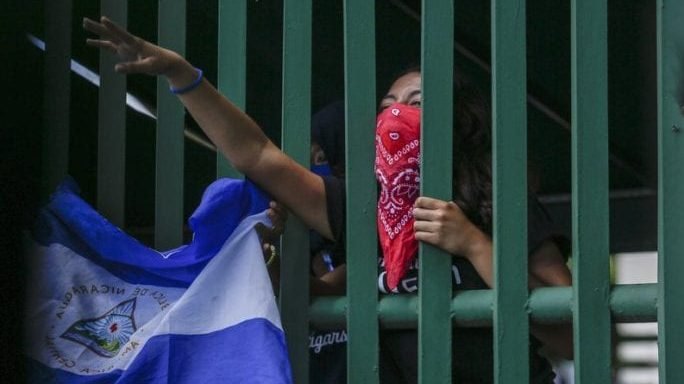 In a file photo, a student, masked to hide her identity for fear of being targeted by security forces or government supporters, waves a Nicaraguan flag during a protest, June 18, 2019. (Alfredo Zuniga/AP via Crux)