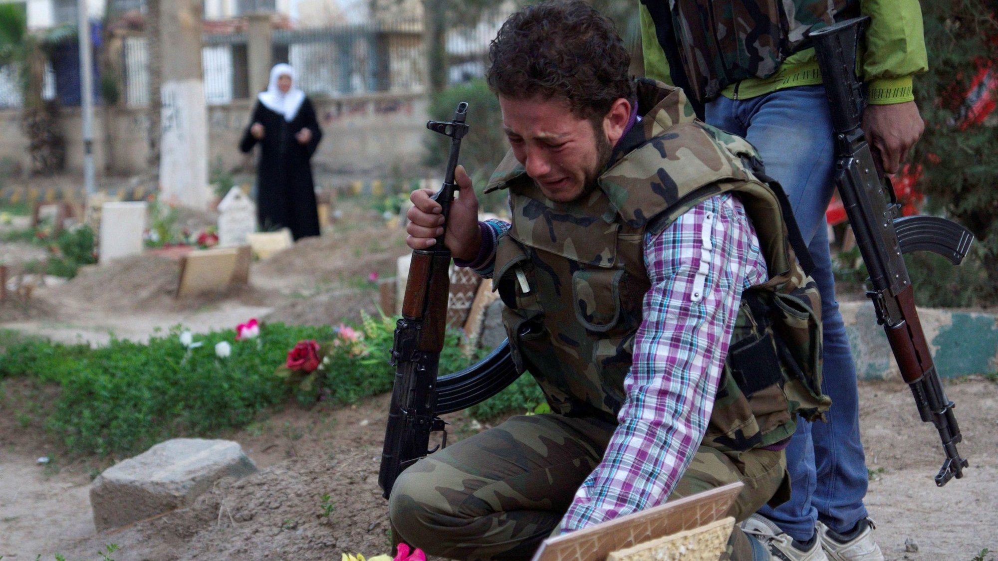 A Free Syrian Army fighter mourns at the grave of his father, killed by what activists said was shelling by forces loyal to Syrian President Bashar Assad, in this 2013 file photo. Syria's civil war has now entered its 10th year. (CNS photo/Khalil Ashawi, Reuters)