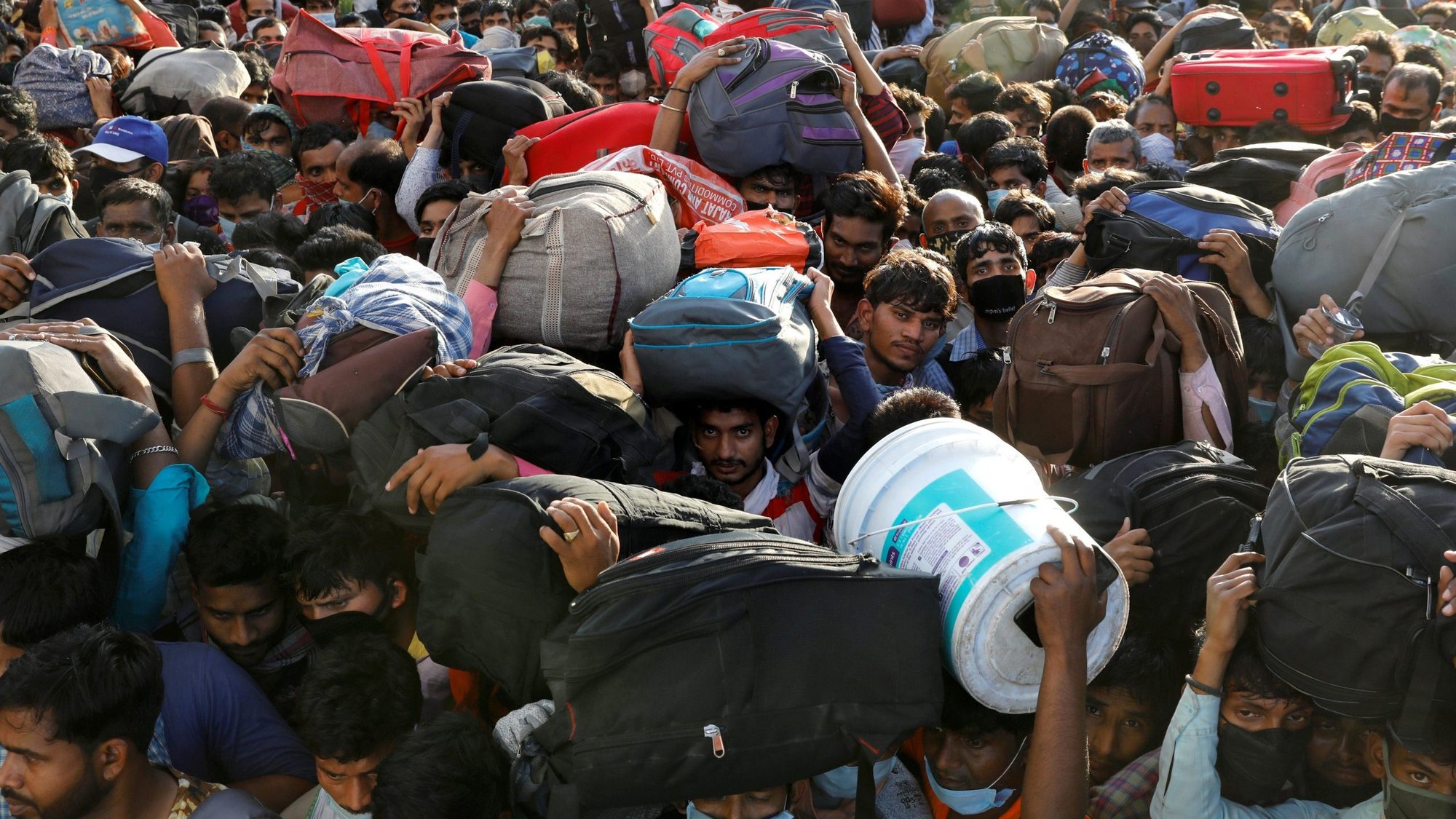 Migrant workers crowd outside a bus station in Ghaziabad, India, March 28, 2020, as they wait to board buses to return to their villages during a 21-day nationwide lockdown to limit the spread of COVID-19. (CNS photo/Anushree Fadnavis, Reuters)
