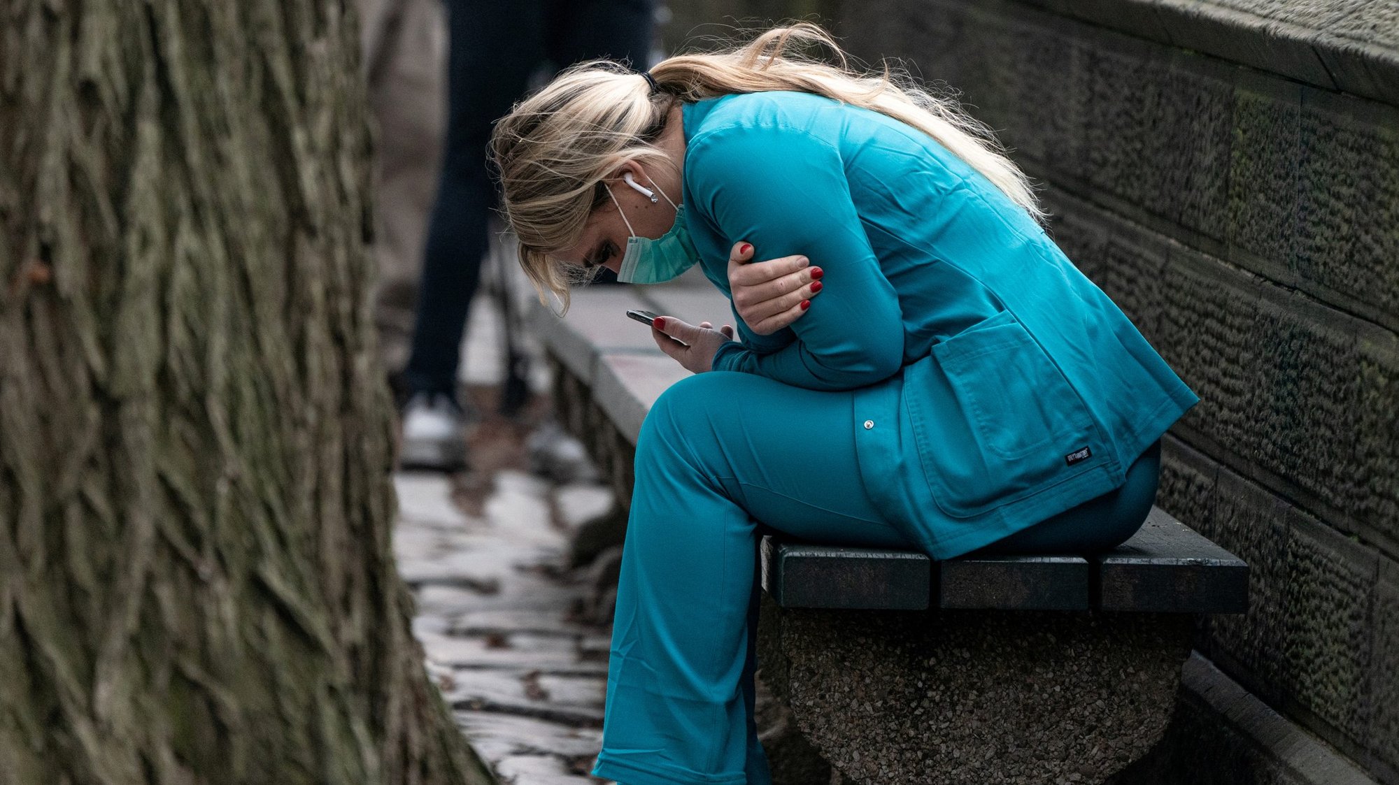 A health care worker in New York City sits on a bench near Central Park March 30, 2020, hunched over and embracing herself. A counselor offers advice on dealing with fear, anxiety, depression or spiritual crisis during the coronavirus (COVID-19) pandemic. (CNS photo/Jeenah Moon, Reuters)