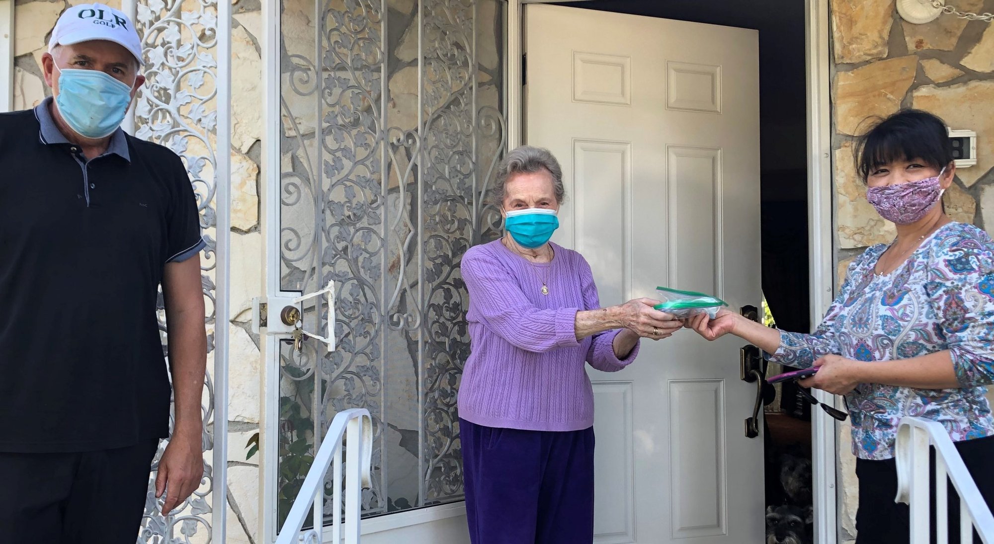 Holly Cavallaro, right, and Father Gerard O’Brien deliver masks to Johanna Raab. Holly volunteers with Team Refuge at Our Lady of Refuge Church. (Lois McKeon)