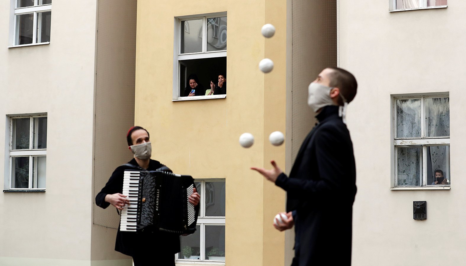 Residents of an apartment building watch street performers on their courtyard in Prague, Czech Republic, April 14, during the coronavirus (COVID-19) pandemic. (Catholic News Service/David W. Cerny, Reuters)