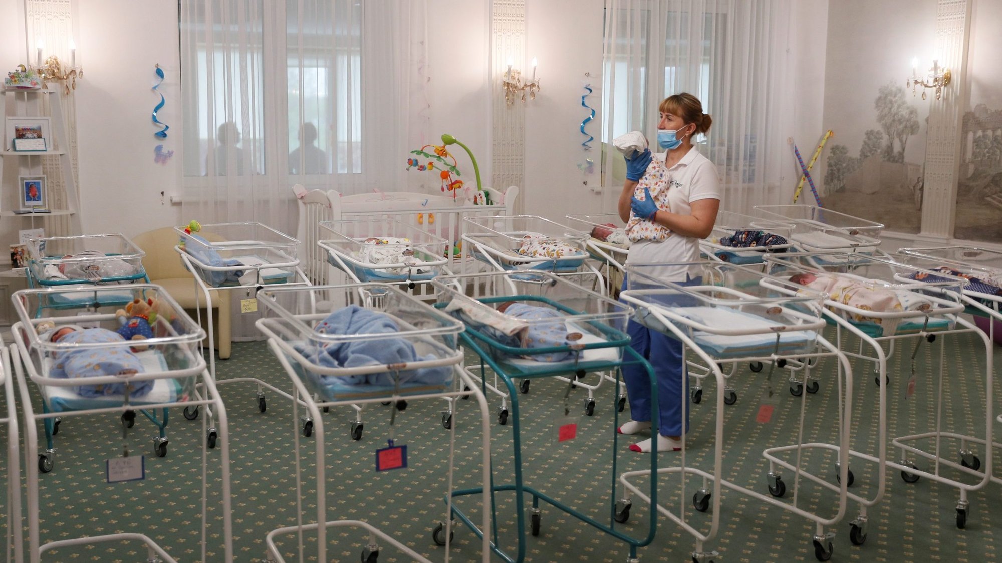 A nurse and newborns are seen in the Hotel Venice, which is owned by BioTexCom. a surrogacy agency in Kyiv, Ukraine, May 14, 2020. Dozens of babies born to surrogate mothers are stranded in Ukraine as the COVID-19 pandemic lockdown prevents their foreign parents from collecting them. The country's Catholic bishops have called for a halt to commercial surrogacy. (CNS photo/Gleb Garanich, Reuters)