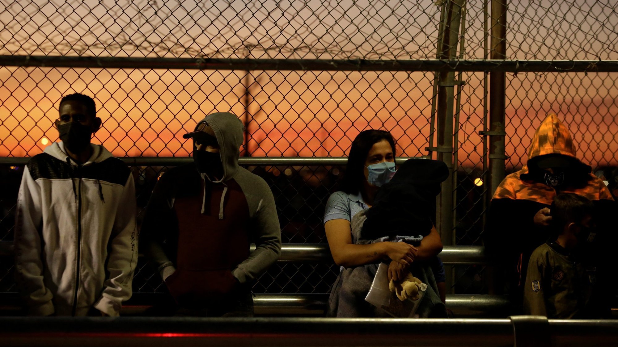 Migrants in the "Remain in Mexico" program line up at the Paso del Norte Mexico-U.S. border bridge in Ciudad Juarez, Mexico, April 21, 2020, to reschedule their United States immigration hearings during the coronavirus pandemic. Catholics who work with migrants on both sides of the border say they are not surprised by the U.S. decision to extend restrictions on nonessential crossings. (CNS photo/Jose Luis Gonzalez, Reuters)