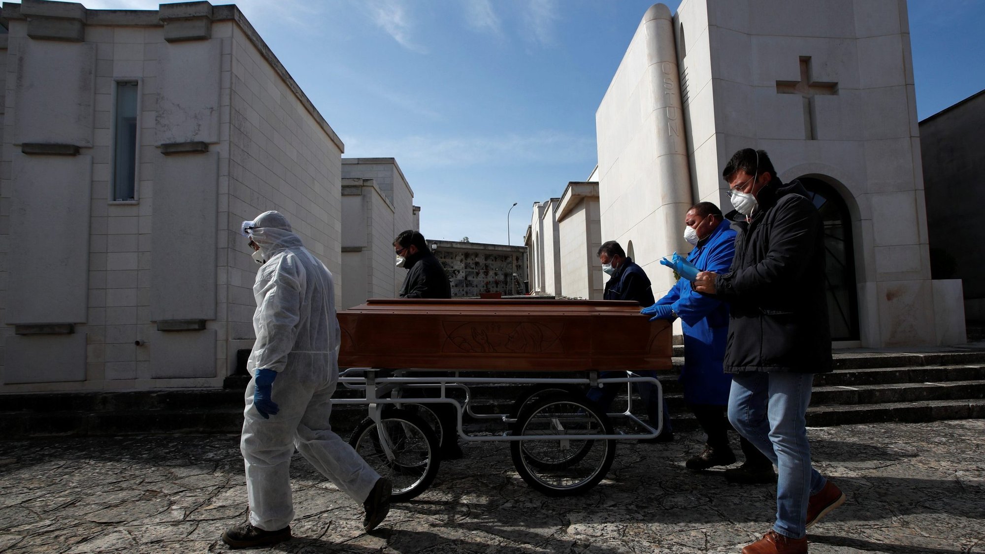 Funeral service workers transport a coffin of a victim of COVID-19 during a ceremony in the southern town of Cisternino, Italy, March 30, 2020. The need for social distancing during the coronavirus pandemic is making the grieving process more difficult for those losing loved ones to the disease. (CNS photo/Alessandro Garofalo, Reuters)