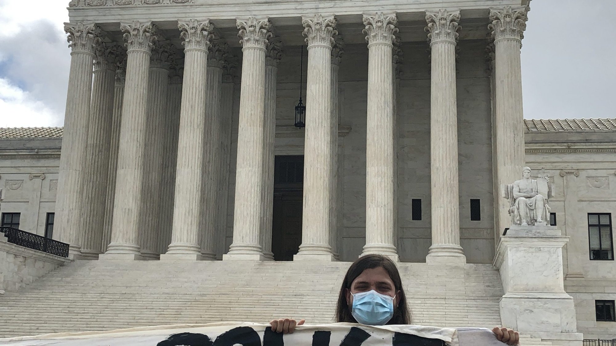 A masked supporter of the Deferred Action for Childhood Arrivals program holds a sign at the U.S. Supreme Court in Washington June 18, 2020, after the justices handed down a 5-4 ruling rejecting President Donald Trump's executive order to cancel DACA. The program was established by the Obama administration to provide legal protections and work authorization to immigrants brought to the U.S. as children by their parents without legal documents. (CNS photo/Rhina Guidos)