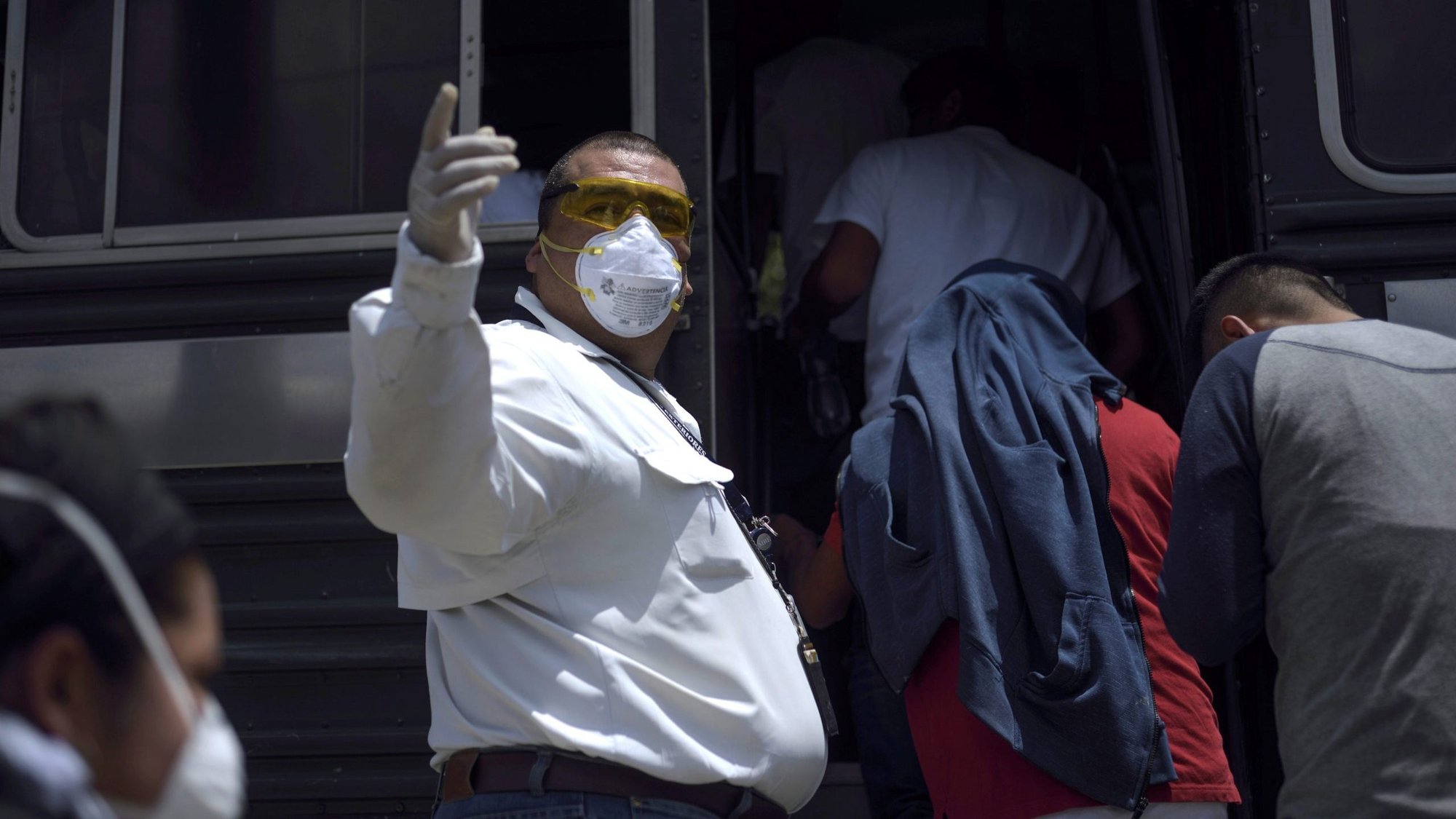 A bus driver outside Guatemala City directs people boarding a bus March 19, 2020, after they were deported from the United States. (CNS photo/Fabricio Alonso, Reuters)