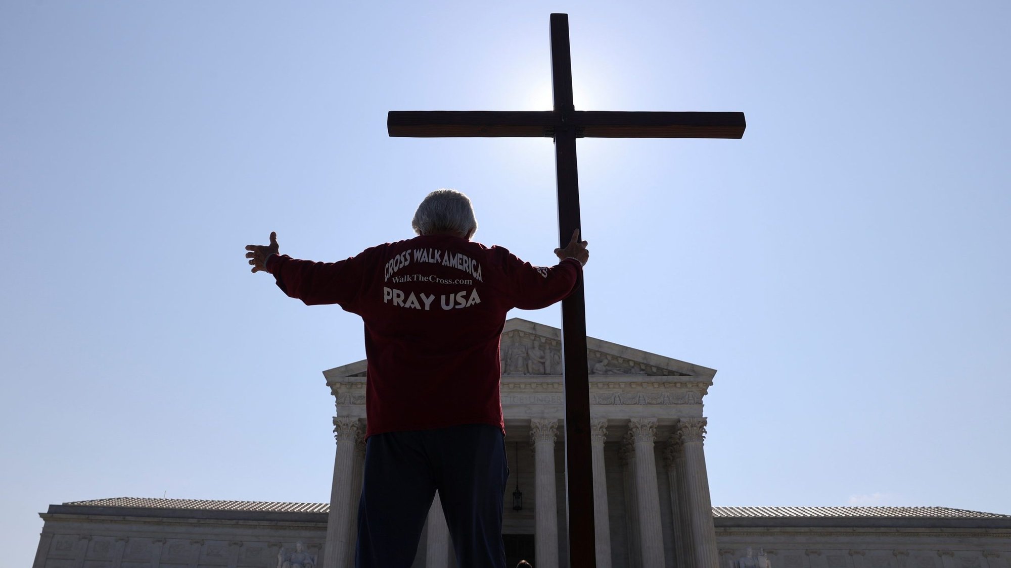 A demonstrator in Washington holds a large cross outside the U.S. Supreme Court July 8, 2020. (CNS photo/Jonathan Ernst, Reuters)