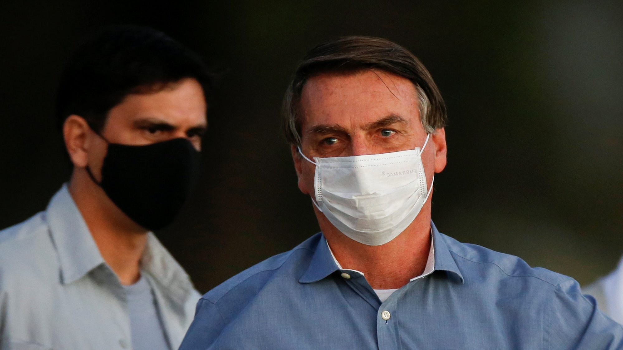 Brazilian President Jair Bolsonaro, wearing a protective mask, holds a banana before a ceremony of lowering the national flag for the night at the Alvorada Palace in Brasilia July 24, 2020, during the COVID-19 pandemic. (CNS photo/Adriano Machado, Reuters)