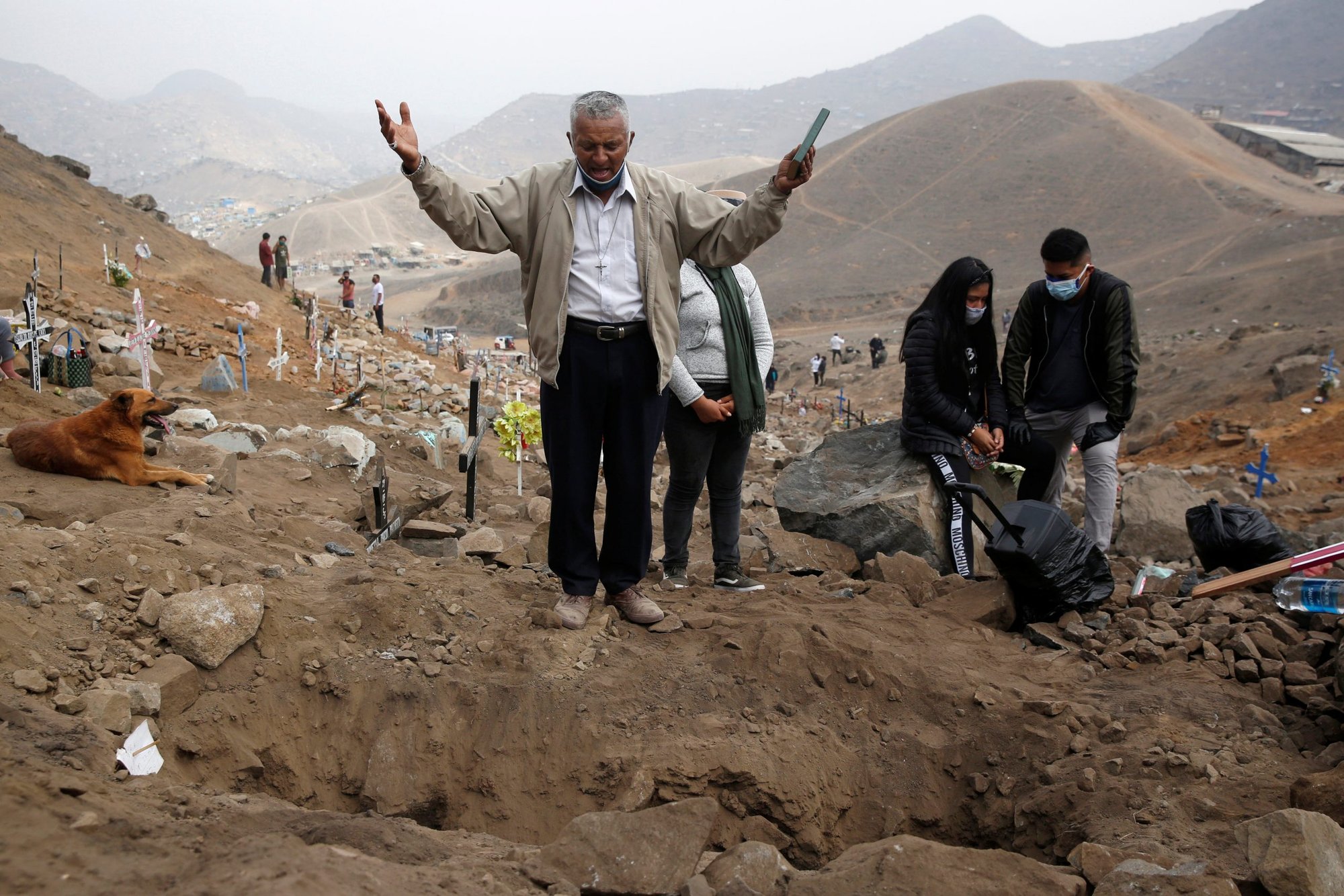 A man holding a Bible prays at a cemetery in Lima, Peru, May 27, during a burial for a person who died from COVID-19. (Catholic News Service/Sebastian Castaneda, Reuters)