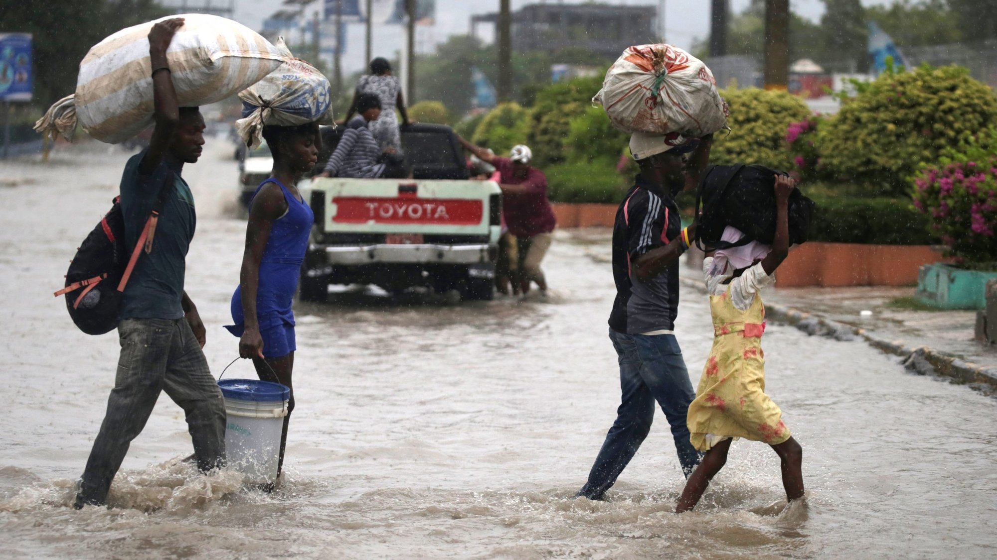 People cross a flooded street in Port-au-Prince, Haiti, Aug. 23, 2020, during the passage of Tropical Storm Laura. (CNS photo/Andres Martinez Casares, Reuters)