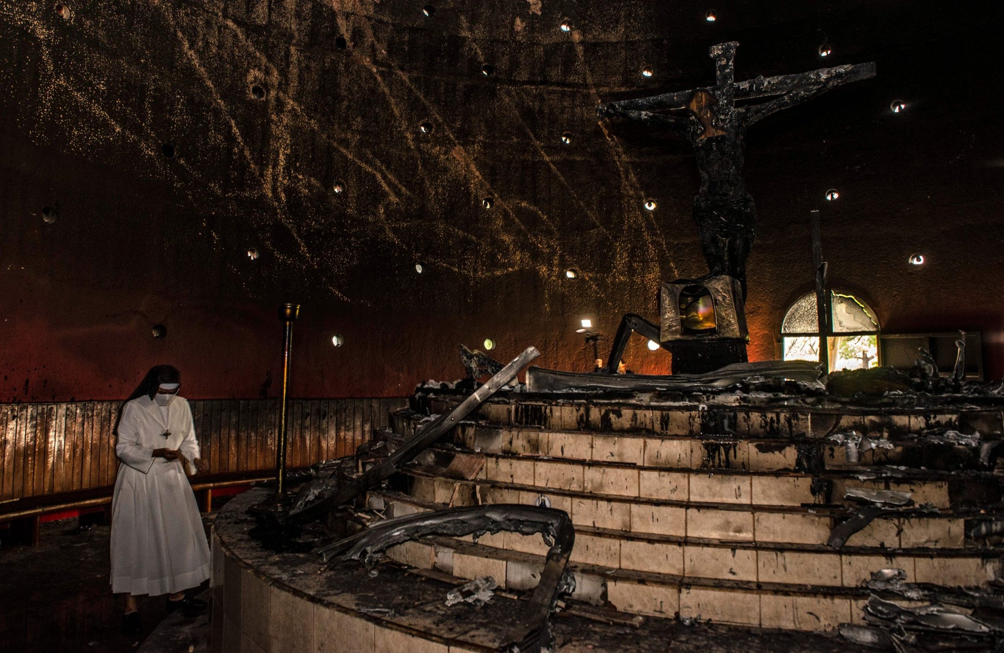 A nun prays next to the charred remains of the image of "Christ's Blood" after an attack with a Molotov cocktail at the Cathedral in Managua on July 31, 2020. An unidentified person attacked the Managua Cathedral with a Molotov cocktail, damaging an image venerated by the Nicaraguan Catholic faithful. (Photo by Oscar NAVARRETE / POOL / AFP)