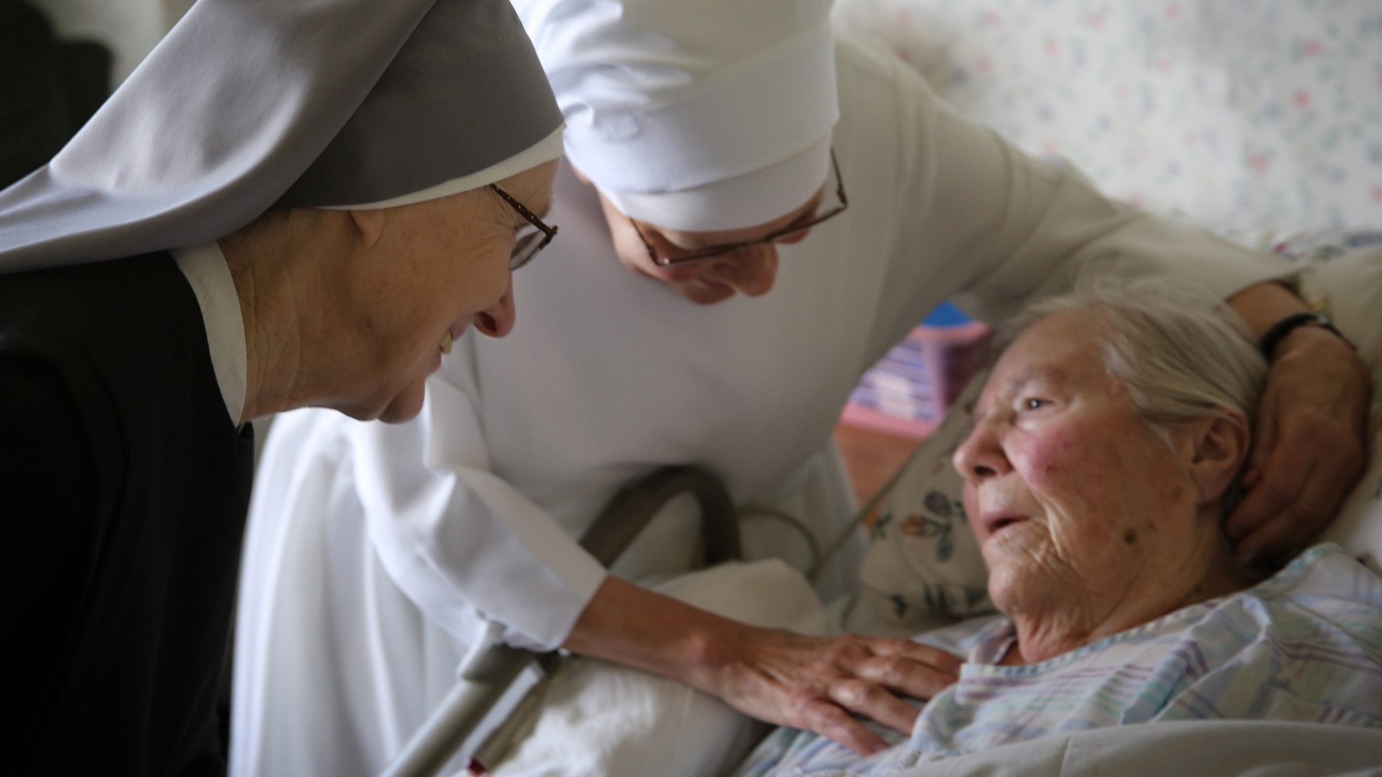 Sister Margaret Patricia Lennon and Sister Anthony Selewicz offer support to a frail resident at Little Sisters of the Poor Jeanne Jugan Residence in San Pedro, Calif., in this 2016 photo. The Little Sisters of the Poor care for the elderly poor in assisted living facilities throughout the U.S. and frequently accompany the dying. (CNS photo/courtesy Little Sisters of the Poor)