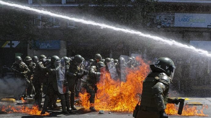 Fire from a molotov cocktail explodes in front of police as a police vehicle shoots water at protesters who marched against the commemoration of the discovery of the Americas, organized by Indigenous groups demanding autonomy and the recovery of ancestral land in Santiago, Chile, Monday, Oct. 12, 2020. (Esteban Felix/AP via Crux)