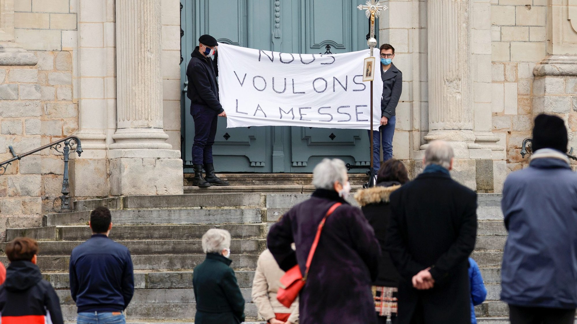 Parishioners wearing protective face masks hold a banner reading "We want the Mass" during an open-air worship in front of the Cathedral of Our Lady of Grace in Cambrai, France, Nov. 22, 2020. (CNS photo/Pascal Rossignol, Reuters)
