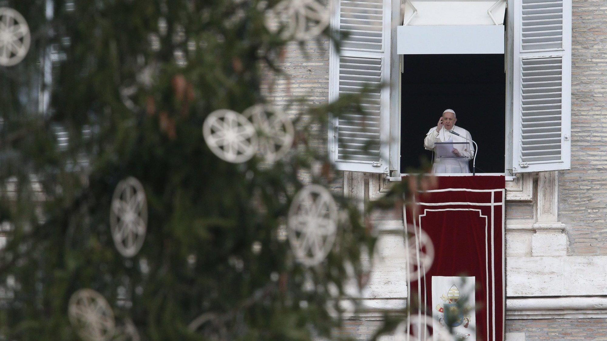 Pope Francis is framed by the Vatican Christmas tree as he delivers his blessing while leading the Angelus from the window of his studio overlooking St. Peter's Square at the Vatican Dec. 8, 2020, the feast of the Immaculate Conception. (CNS photo/Paul Haring)