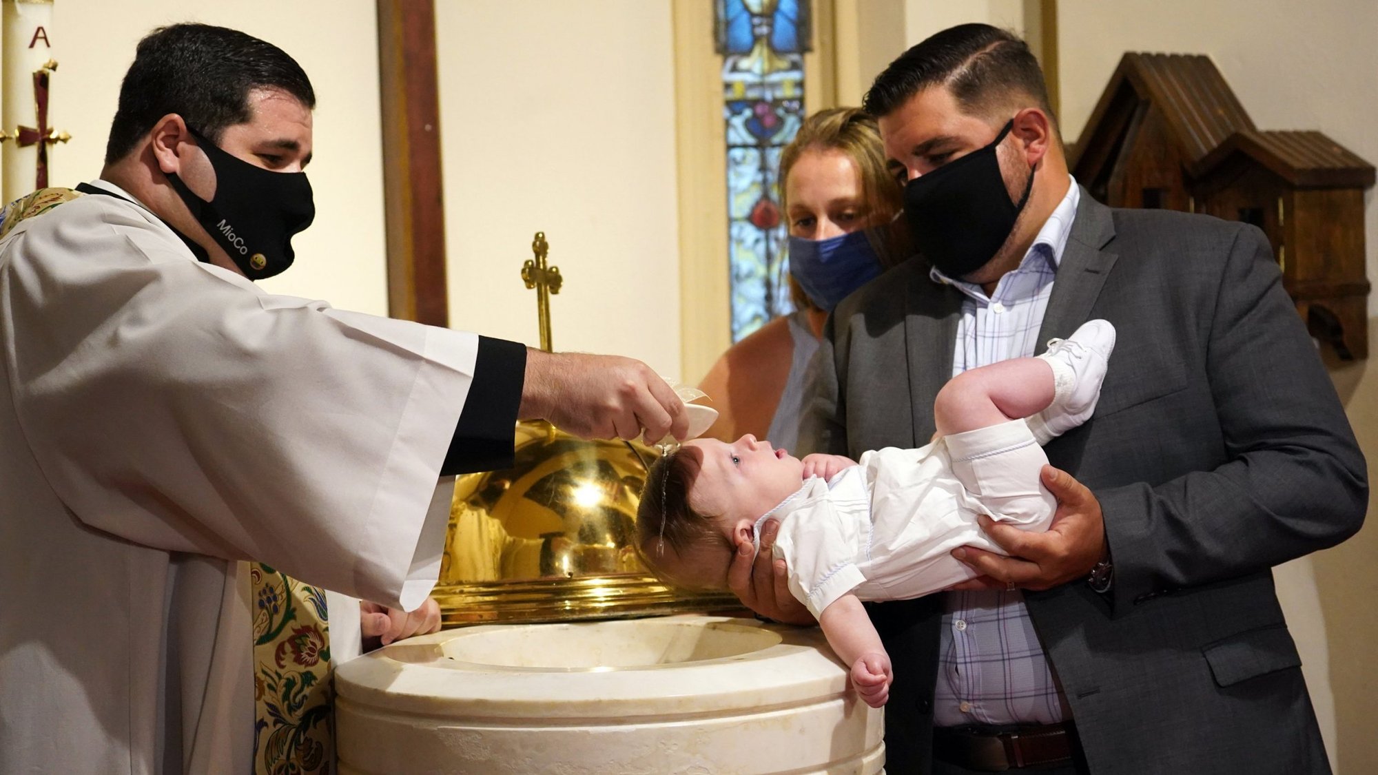 Father Matthew Browne pours water over the head of 5-month-old Rocco Richard O'Toole during his baptism Aug. 16, 2020, at St. Dominic Church in Oyster Bay, N.Y. Also pictured are Rocco's parents, Lauren and Tim O'Toole. The ceremony occurred on the traditional feast day of the child's patron, St. Rocco, who is believed to be a protector against plagues and all contagious diseases. (CNS photo/Gregory A. Shemitz)