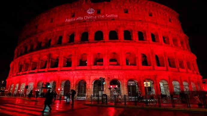 The Colosseum in Rome is lit in red Feb. 12, 2018, to draw attention to the persecution of Christians around the world as part of Aid to the Church in Need's "Red Wednesday" campaign. Aid to the Church in Need says its deceased founder was credibly accused of sexual assault. (CNS/Remo Casilli, Reuters via Crux)
