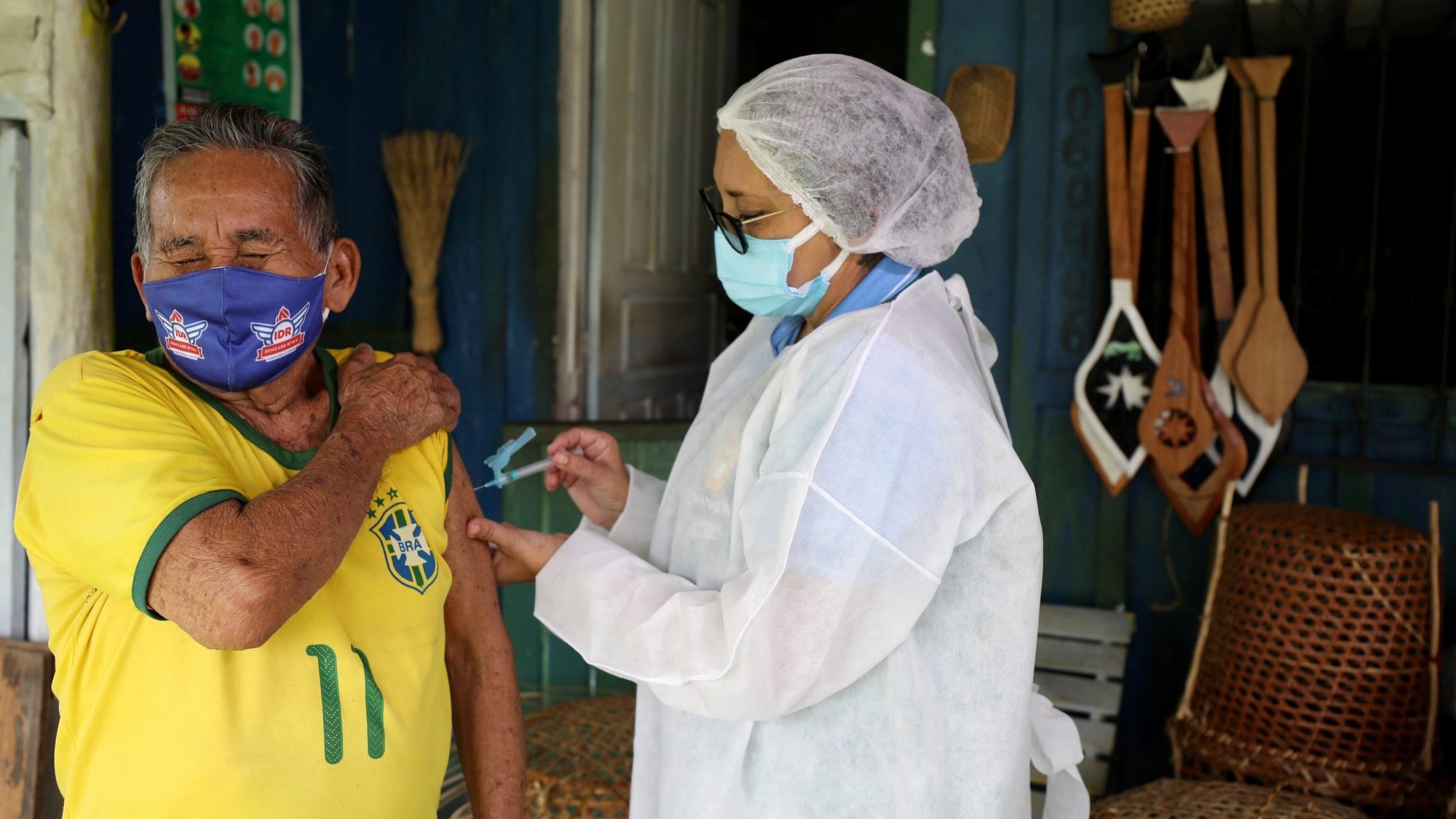 An Indigenous man receives the AstraZeneca/Oxford COVID-19 vaccine from a municipal health worker in the Sustainable Development Reserve of Tupe in Manaus, Brazil, Feb. 9, 2021. (CNS photo/Bruno Kelly, Reuters)