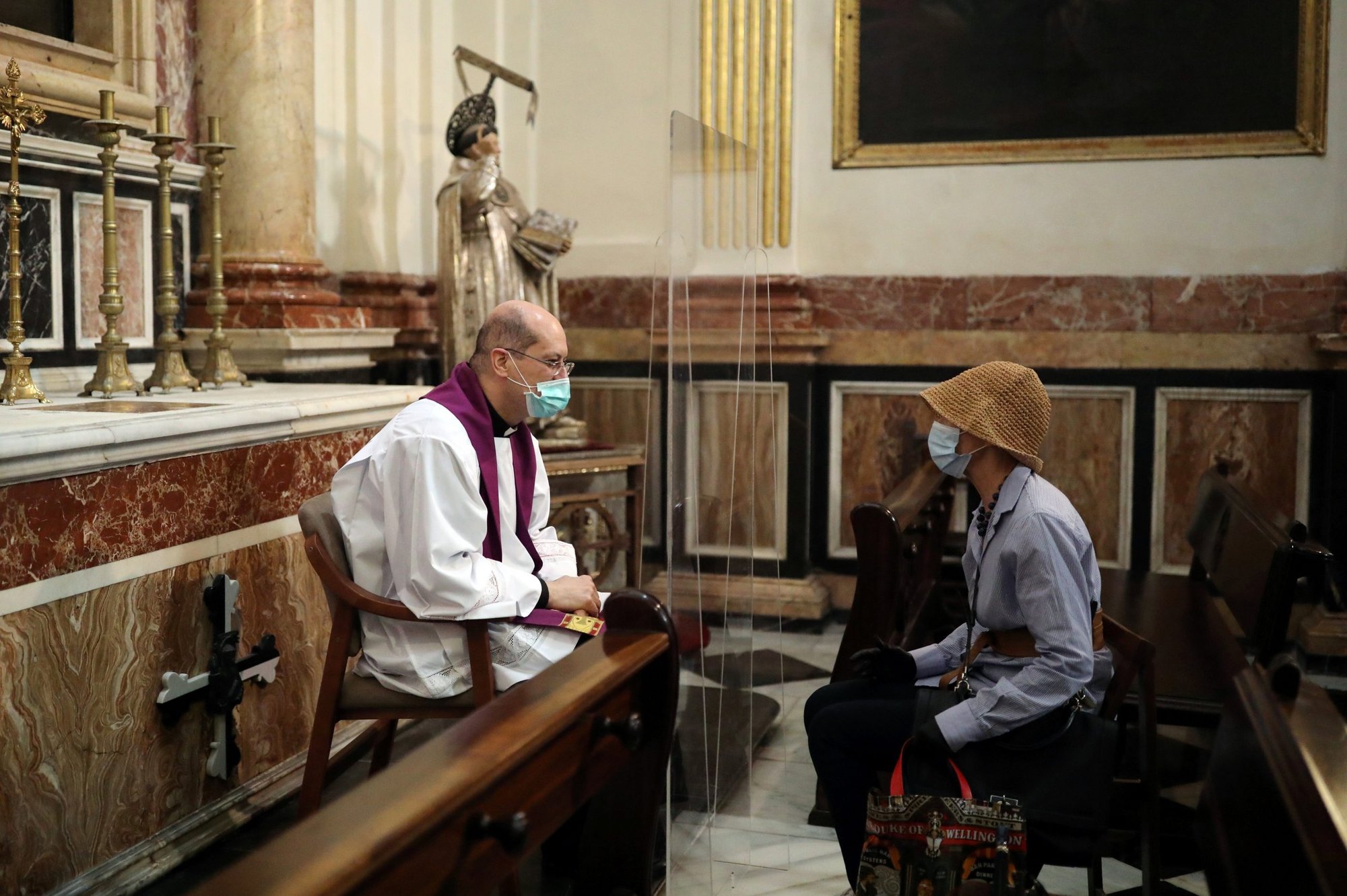 A priest hears confession inside the cathedral in Valencia, Spain, May 19, 2020. (Catholic News Service/Nacho Doce, Reuters)