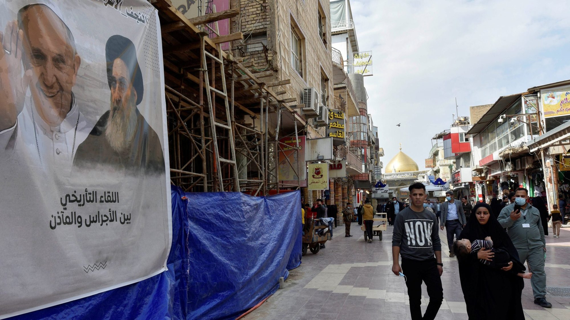 People walk past a poster of Pope Francis and Ayatollah Ali al-Sistani, one of Shiite Islam's most authoritative figures, in Najaf, Iraq, March 4, 2021, ahead of the pope's planned March 5-8 visit to Iraq. The two religious leaders are scheduled to meet in Jajaf. (CNS photo/Alaa Al-Marjani, Reuters)