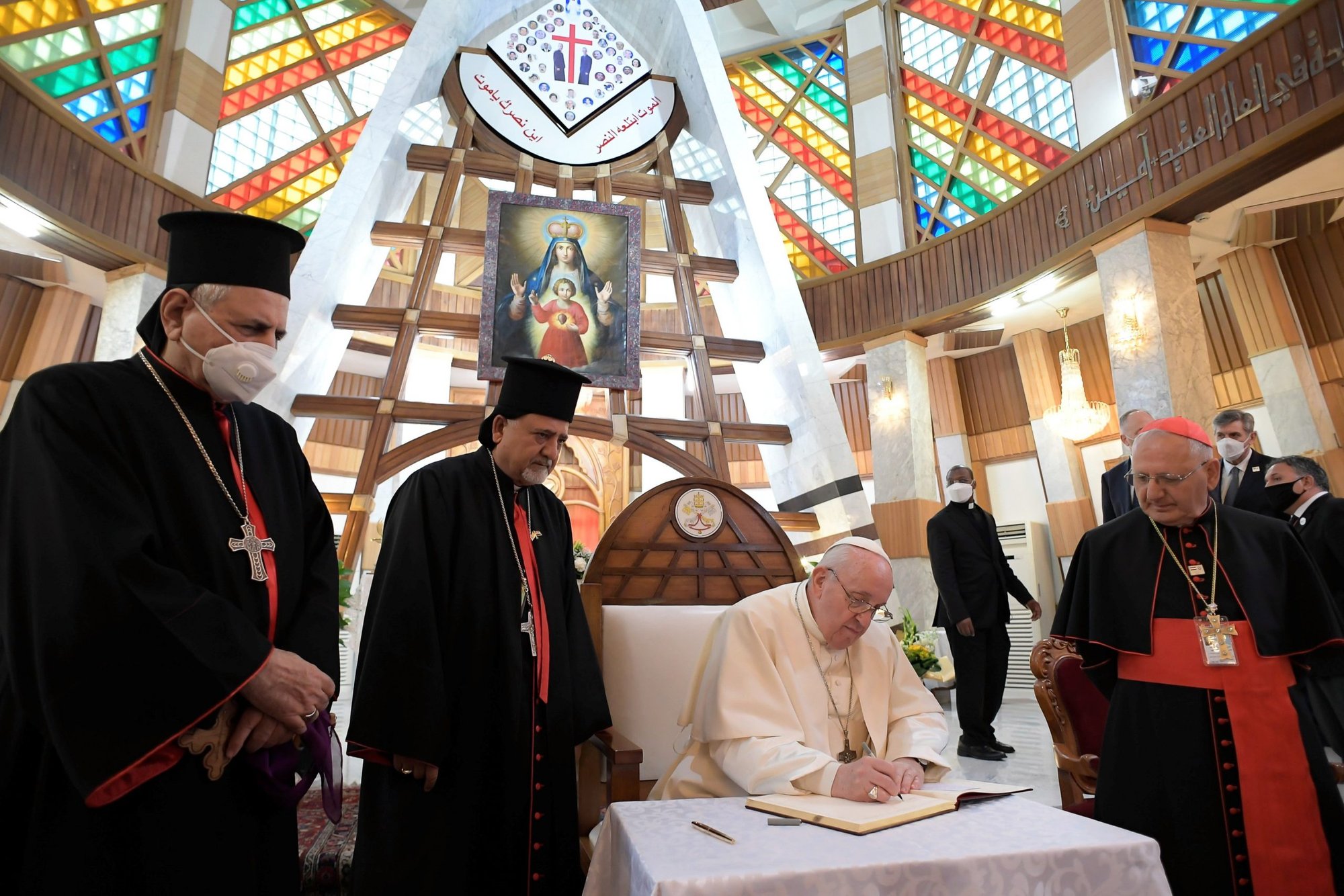Pope Francis signs a book with a message for Syriac Catholics at the Cathedral of Our Lady of Deliverance in Baghdad March 5, 2021. Also pictured, from left: Syriac Catholic Patriarch Ignace Joseph III Younan, Syriac Catholic Archbishop Ephrem Yousif Mansoor Abba of Baghdad and Chaldean Patriarch Louis Sako of Baghdad. (CNS photo/Vatican Media via Reuters)