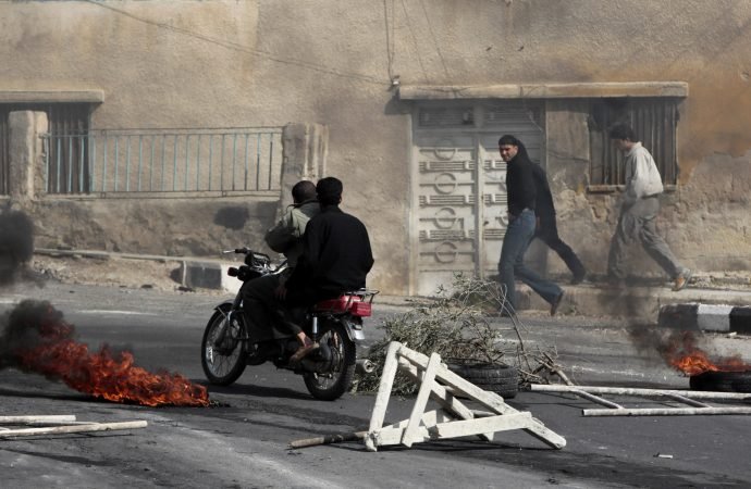 In this March 23, 2011, file photo, anti-government protesters pass burning tires set alight by the protesters following clashes with Syrian security forces in the southern city of Daraa, Syria. The decision by Syrian President Bashar Assad to crush the initially peaceful protests in March 2011 propelled Syria into a civil war that has killed more than a half million people. (Hussein Malla/AP via Crux)