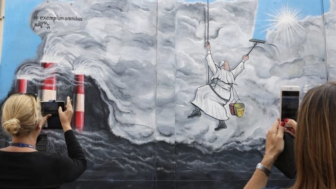 People photograph a graffiti depicting Pope Francis cleaning the sky from pollution, painted on a wall of Albano, near Rome, before the start of the pontiff visit, Saturday, Sept. 21, 2019. The graffiti realized by artist Maupal, Mauro Pallotta and named 'Exemplum Omnibus' (Example for All) was inspired by the encyclical 'Laudato Si' (Praise Be) where is declared an urgent need for the political and spiritual conversion of global leaders and individuals to dedicate themselves to curbing climate change and ending policies and personal habits that destroy creation. (Andrew Medichini/AP.)
