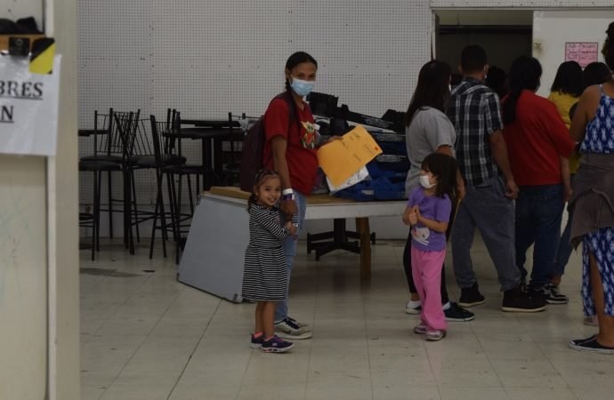 A mother and daughter wait in line for a fresh set of clothes at the Catholic Charities of the Rio Grande Valley Humanitarian Respite Center in McAllen, Texas (John Lavenburg)