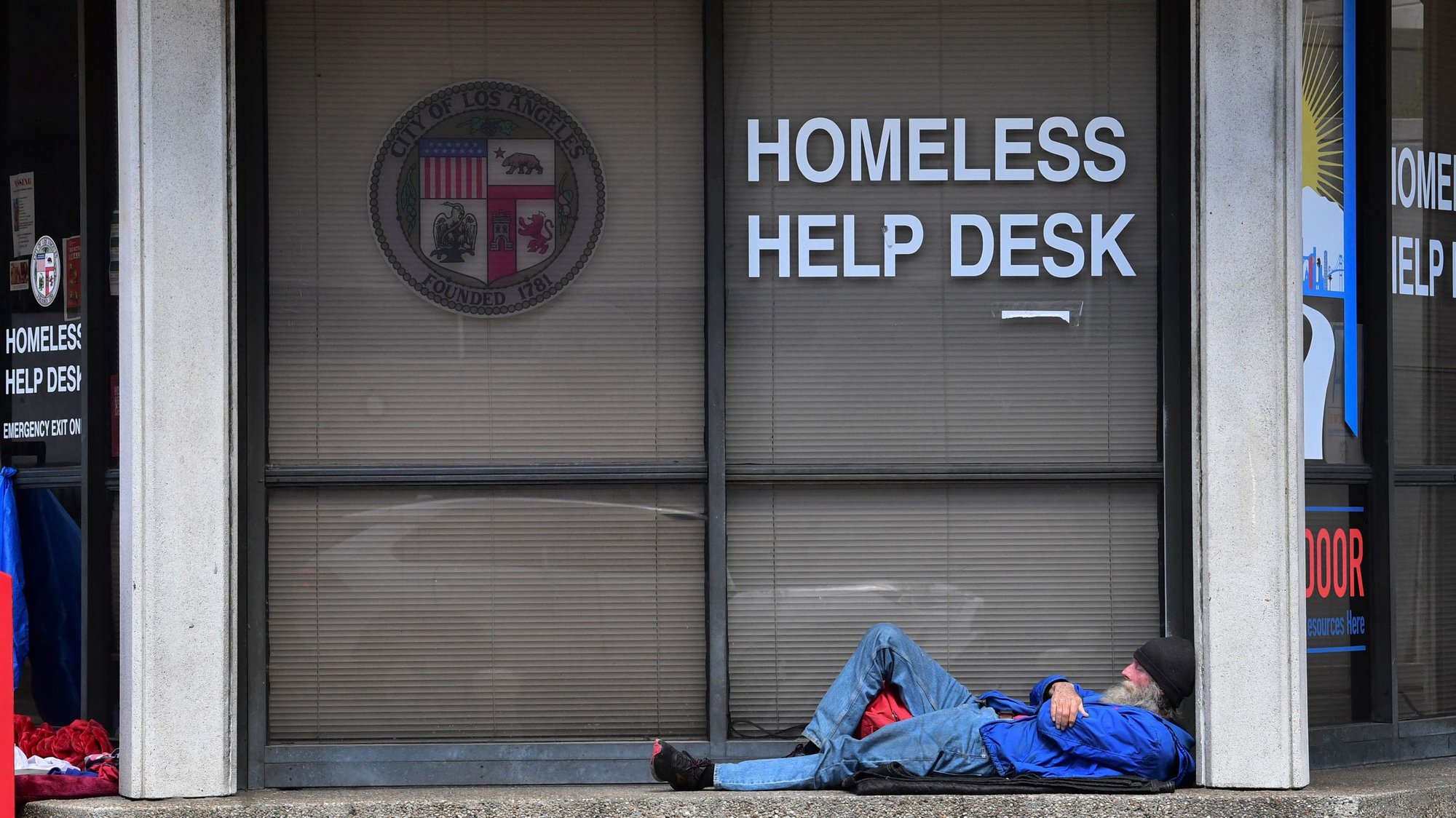 A man sleeps outside the Homeless Help Desk kiosk in the Skid Row community of Los Angeles, California on April 26, 2021. (Photo by FREDERIC J. BROWN/AFP via Getty Images)