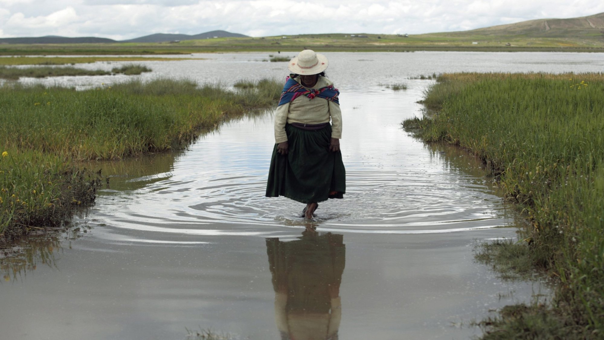 An indigenous woman is pictured in a file photo wading through floodwaters on a farm after heavy rains near La Paz, Bolivia. (CNS photo/Gaston Brito, Reuters)
