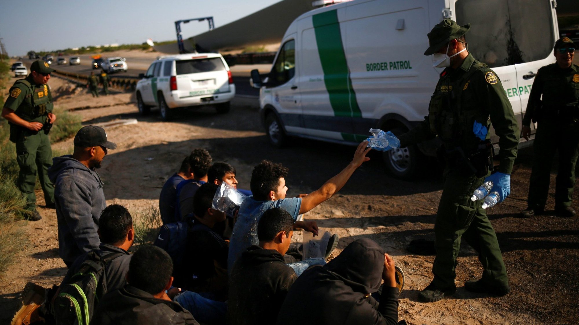 A U.S. Customs and Border Protection agent in Sunland Park, N.M., gives bottles of drinking water to migrants from Central America who were detained after crossing into the United States July 15, 2021. (CNS photo/Jose Luis Gonzalez, Reuters)