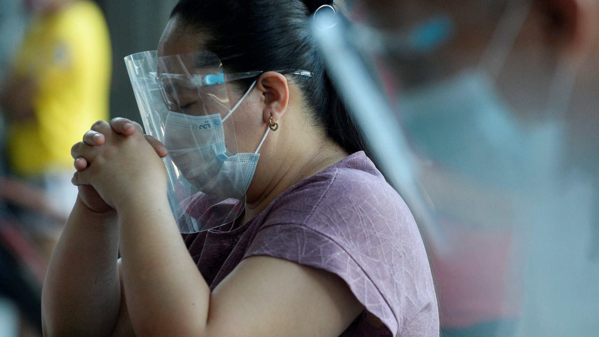 A woman wearing a protective mask and face shield prays during Easter Mass outside St. Peter Parish: Shrine of Leaders in Manila, Philippines, April 4, 2021, during the COVID-19 pandemic. (CNS photo/Lisa Marie David, Reuters)